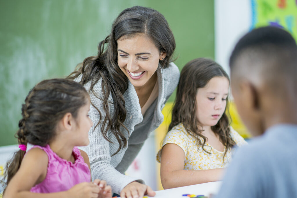 A teacher joyfully teaches her students in the classroom, creating a positive learning environment and showcasing soft skills for educational leaders.