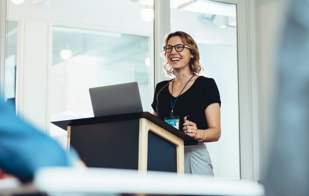 Woman standing at a podium with laptop while giving a speech.