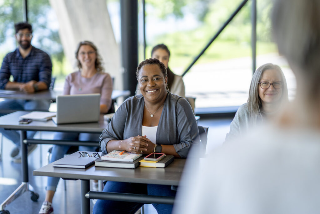 A class of mature students sit in class together as they listen attentively to the teacher